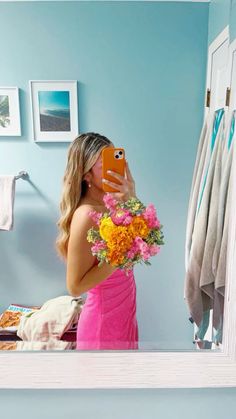 a woman taking a selfie in front of a mirror with flowers on her bouquet