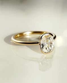 a gold ring with a white diamond in the center on a white surface, close up