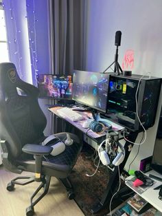 a gaming chair sitting in front of a computer desk with two monitors and headphones on it