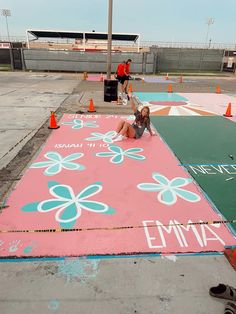 a woman laying on top of a large pink and green mat with flowers painted on it