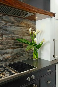 a vase with flowers in it sitting on top of a kitchen counter next to an oven