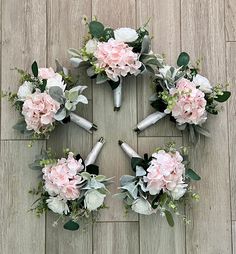 a bunch of flowers arranged in the shape of a cross on a wooden floor with greenery