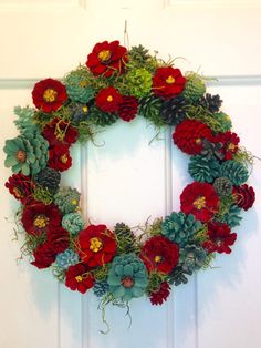 a wreath made out of pine cones and red flowers