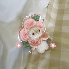 a crocheted stuffed animal laying on top of a white bed sheet with pink flowers