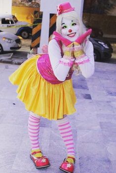 a clown dressed in yellow and pink poses for the camera