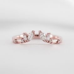 two rose gold wedding rings with pear shaped diamonds on the sides, set against a white background