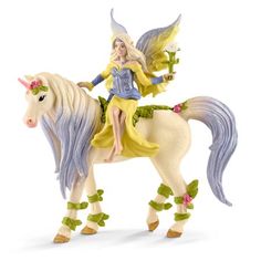 a figurine of a fairy sitting on top of a horse with flowers in her hair