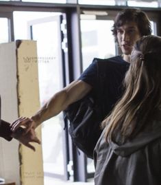 two people are standing in front of a door and one person is holding out their hand