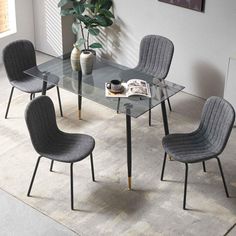 a glass table with four chairs and a vase on it in a living room area