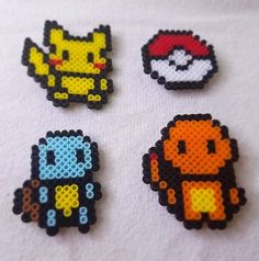 four pixel art magnets are shown on a white tablecloth and one has an image of the character from pokemon