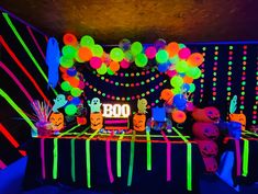 a table with neon lights and balloons in the shape of boo's on it