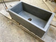 a large gray sink sitting on top of a wooden pallet next to a chain