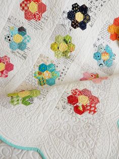 a close up of a quilt on a bed with many different colors and shapes in it