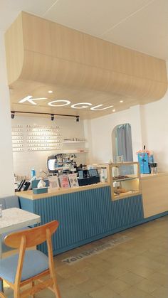 the interior of a coffee shop with blue counter tops and wooden chairs in front of it