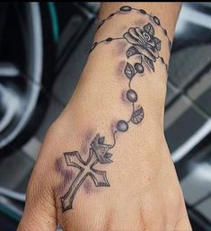 a hand with a cross and flowers on it