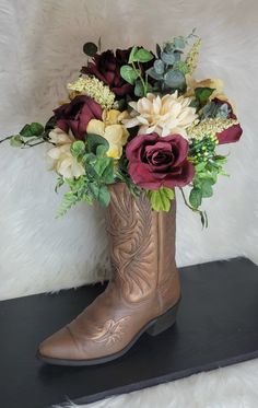 a cowboy boot with flowers in it sitting on a black shelf next to a white fur wall