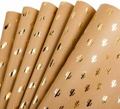 six rolls of brown wrapping paper with gold foiled letters and cactus designs on them