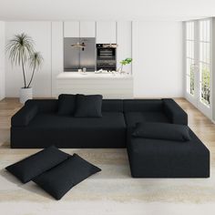 a large black couch sitting on top of a wooden floor next to a white counter