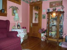 a living room with pink walls and wooden floors is pictured in this image from the front door