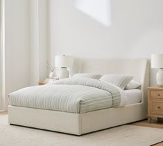 a white bed sitting in a bedroom on top of a wooden floor