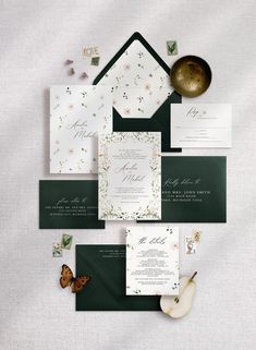 the wedding stationery is laid out on top of each other, including green envelopes and