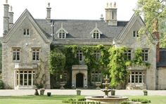 a large stone house with ivy growing on it's walls and an ornamental fountain in the front yard