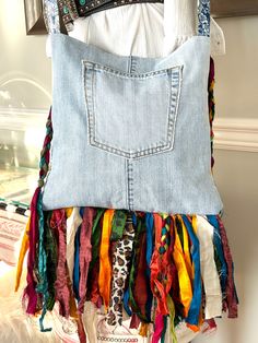 a purse made out of old jeans with colorful ribbons hanging from it's back