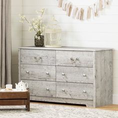 a white dresser with drawers in a living room next to a window and rug on the floor