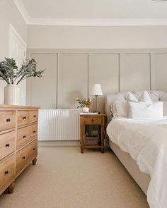 a bedroom with a bed, dresser and plant in the corner on top of it