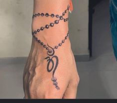 a person's hand with a tattoo on it and a chain around the wrist