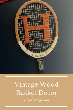 an old racquet with the letter h on it is hanging from a wall