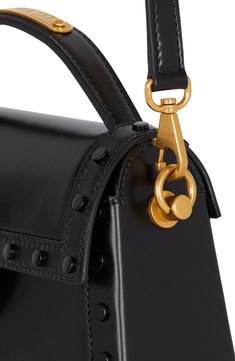 Balmain expands the B-Buzz line with this new handbag crafted of glazed calfskin in a structured silhouette traced with tonal disc studs. A removable crossbody strap offers an additional carrying option, while engraved logo hardware puts the label's signature stamp on the look. Magnetic-snap flap closure Top carry handle; removable crossbody strap Exterior slip pocket Interior zip pocket; card slot Structured silhouette with flat base and protective metal feet Leather Made in Italy Designer Hand Signature Stamp, Pocket Card, Black Leather Tote Bag, Balmain Paris, Pierre Balmain, Crossbody Tote Bag, Engraved Logo, Crossbody Tote, Handle Bag