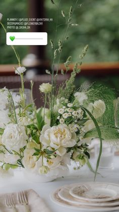 the table is set with white flowers and place settings