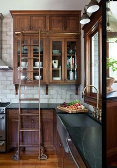 a ladder is in the middle of a kitchen with wooden cabinets and black counter tops