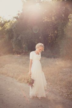 a woman in a white dress is walking down a dirt road with her bouquet and the words, who box dress?