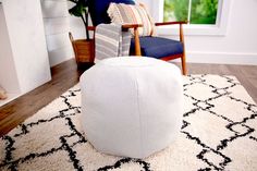 a living room with a large white ottoman on the floor and a chair next to it