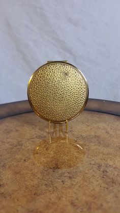 a gold plate sitting on top of a wooden table next to a white wall in the background