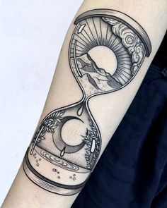 a black and white tattoo with an hourglass on the left arm that is filled with water