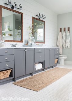 a bathroom with gray cabinets and white walls