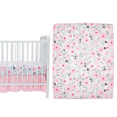 a white crib bed next to a pink and gray flowered baby cotter