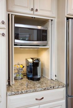 a coffee maker is sitting on the counter in front of a microwave oven and refrigerator