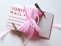 a pink ribbon tied to a white box with scissors on the side and a label that says lorii mail