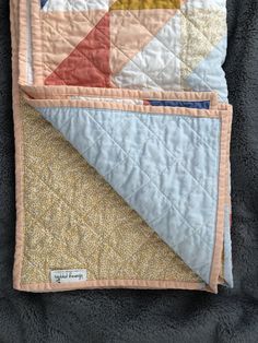 two quilts are laying next to each other on a blanket that has been folded over