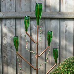 a tree made out of green glass bottles sitting in the grass