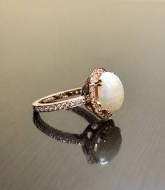 an opal and diamond ring on a reflective surface