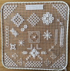 a piece of white lace with flowers on it sitting on top of a wooden table