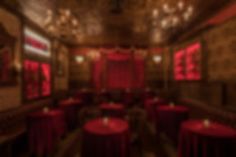 a blurry photo of a restaurant with red tables and chairs in the center, along with chandeliers hanging from the ceiling