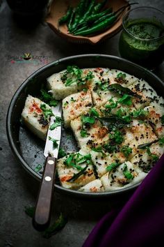 a pan filled with food and a knife on top of it next to some green beans