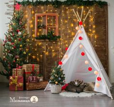 a teepee with christmas lights on it and presents in front of the wall behind it