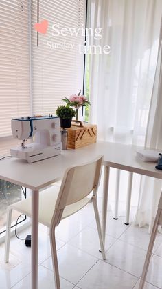 a sewing machine sitting on top of a white table next to a window with sheer curtains